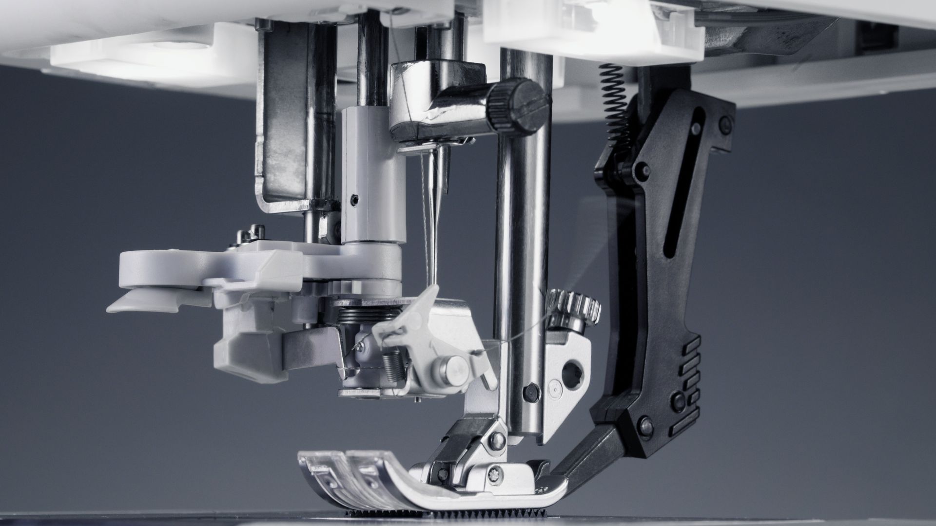 Close-up of a sewing machine presser foot stitching fabric with a needle