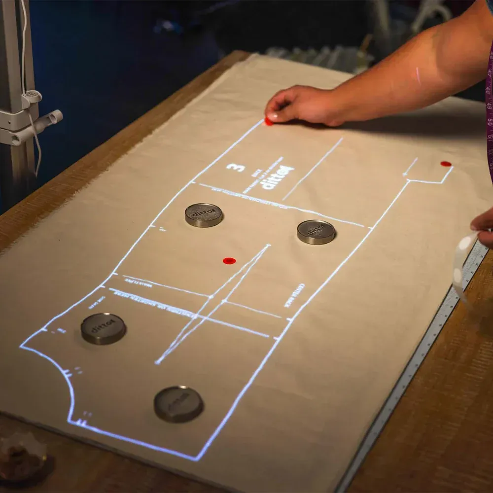Hand guiding a puck on a projected tabletop game board with marked zones and several black pucks