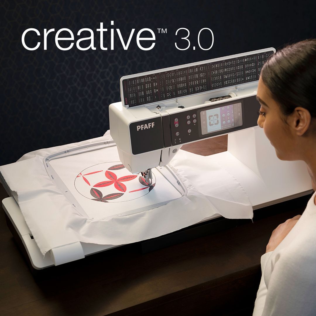 Woman using a Creative 3.0 sewing machine to embroider a red pattern on white fabric.