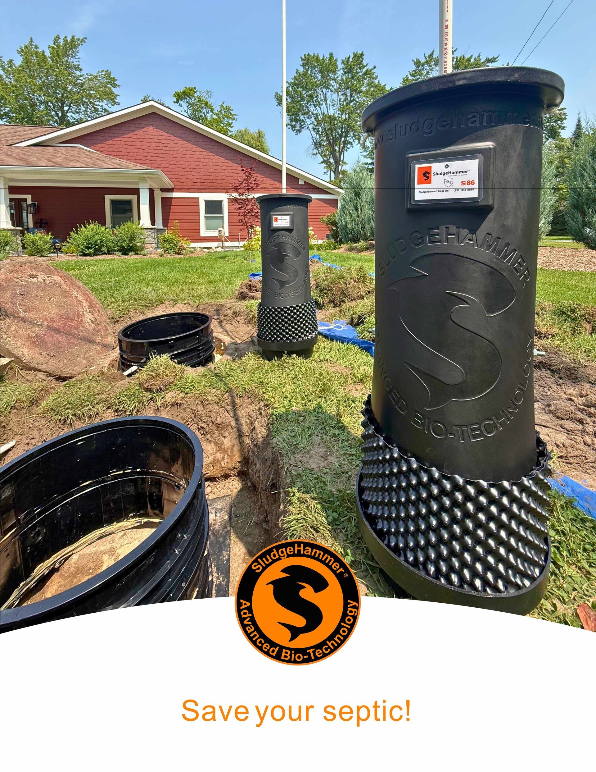 Black cylindrical septic filter units installed in a residential yard near a red house. Logo reads, 