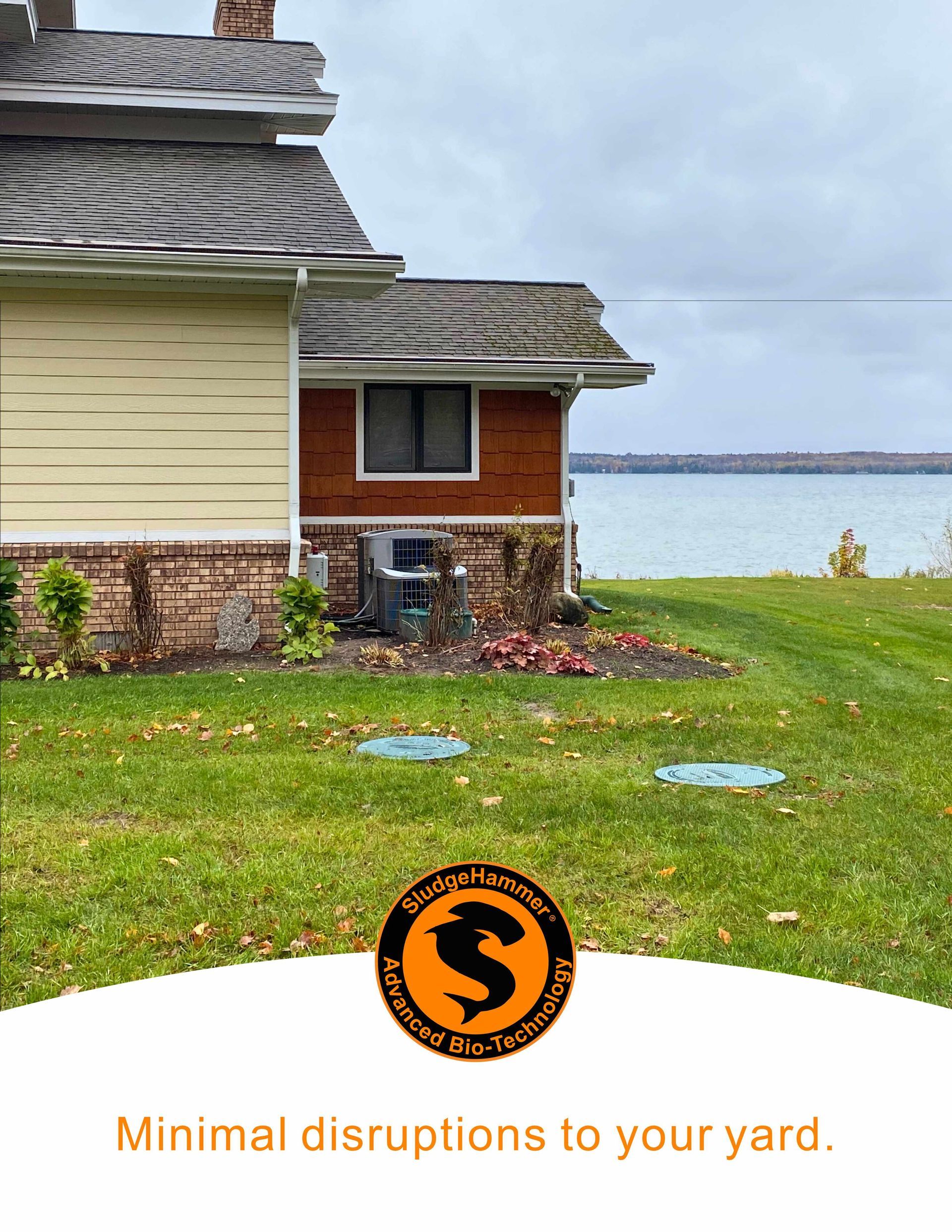 A lakefront home exterior showing a lawn with two access covers and a logo for 