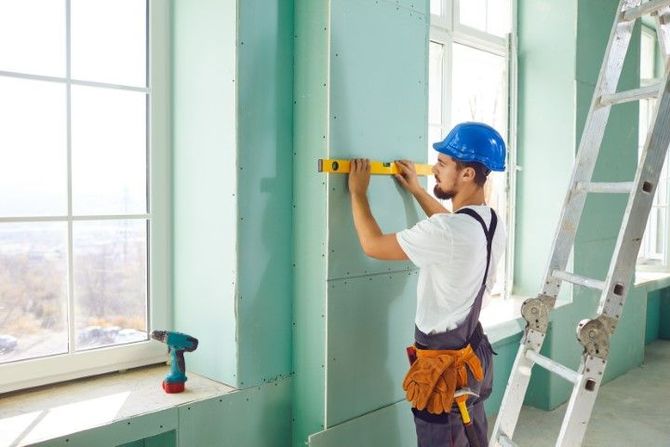 Professional contractor checking wall alignment with a spirit level during a drywall service in Moreno Valley, CA.
