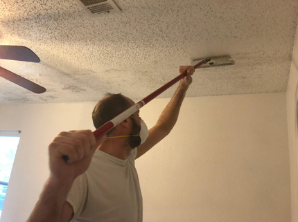 Worker scraping textured popcorn finish off a ceiling during a professional drywall service in Moreno Valley, CA.
