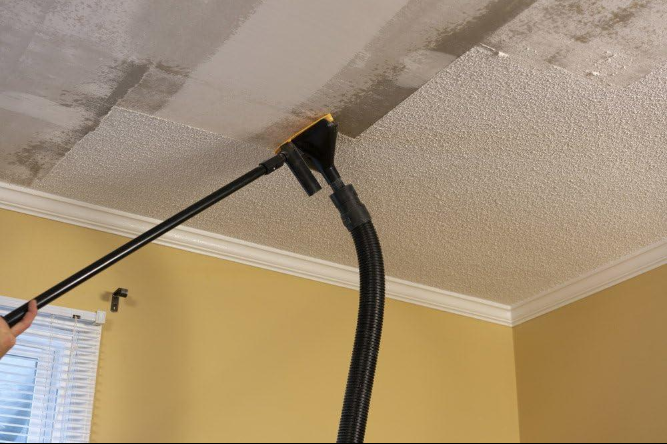 Professional drywall worker removing outdated popcorn ceiling texture from a home in San Jacinto, California.