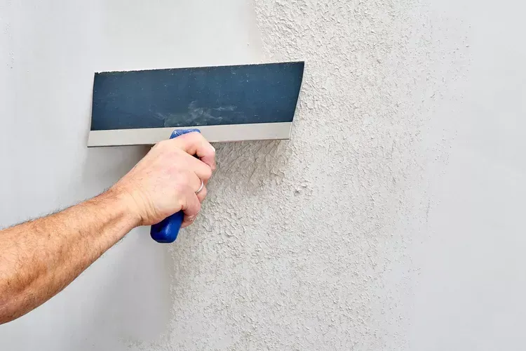 Worker applying joint compound with a taping knife during a drywall service in Moreno Valley, CA