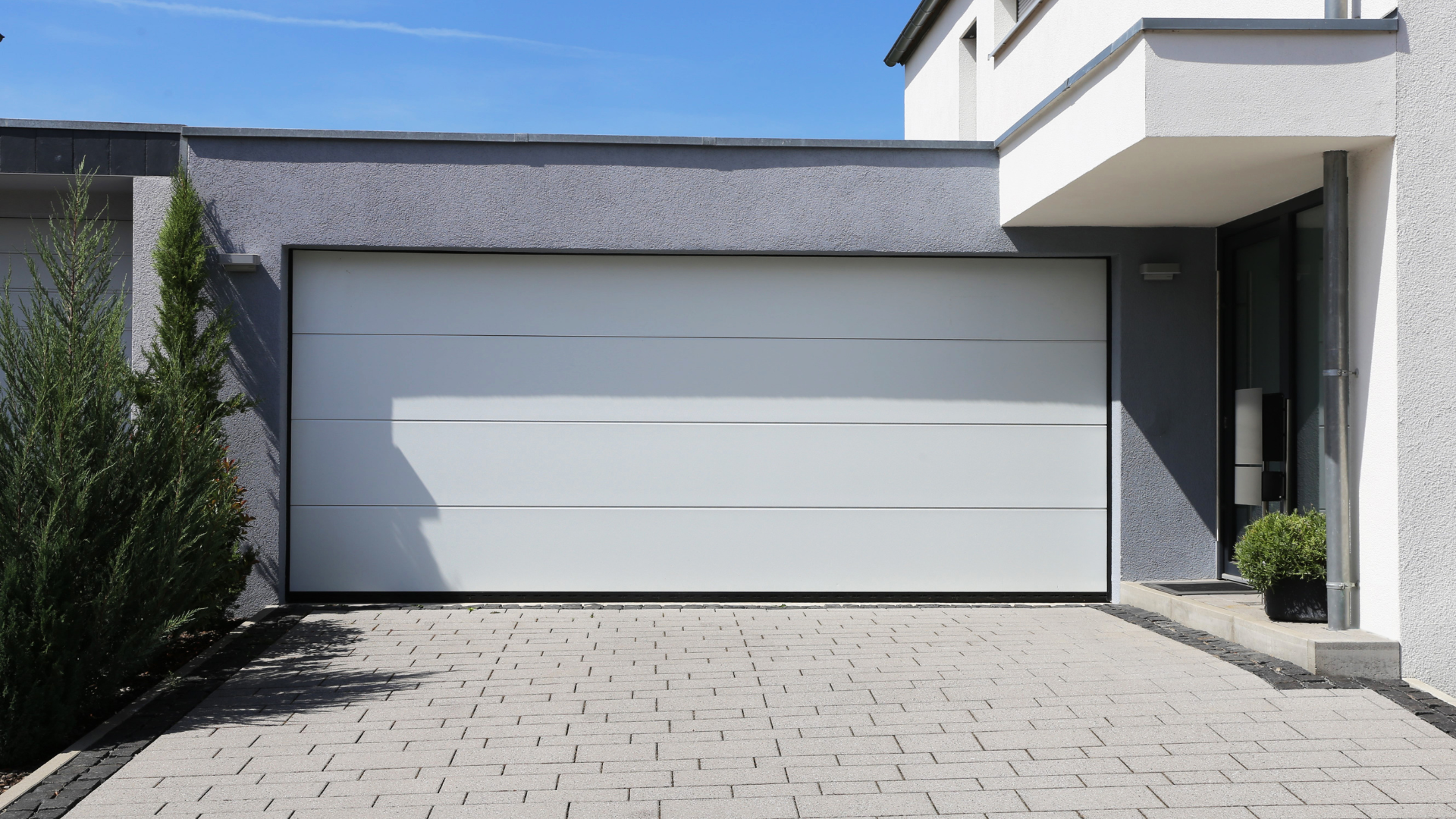 A white garage door is sitting in front of a house.