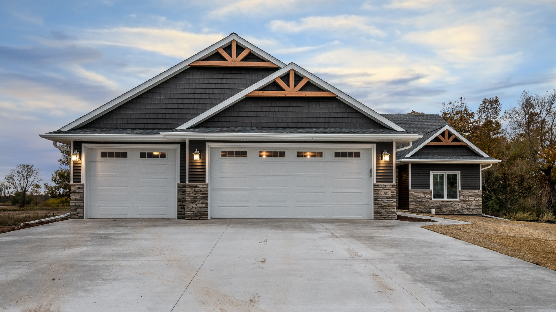 A large house with three garage doors and a driveway.