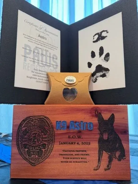 Wooden dog memorial plaque with paw print and a framed certificate behind it