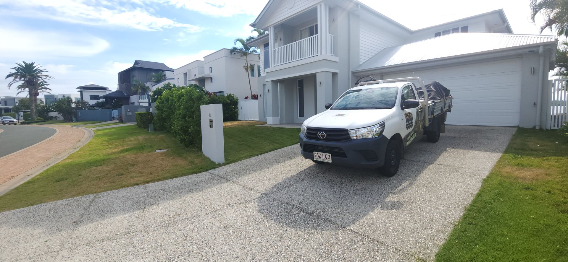 White SUV parked in a driveway beside a modern two-story house on a sunny day