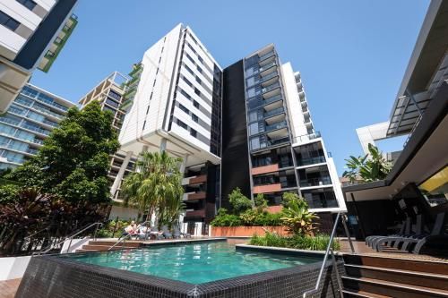 Modern apartment buildings beside a turquoise pool under a clear blue sky
