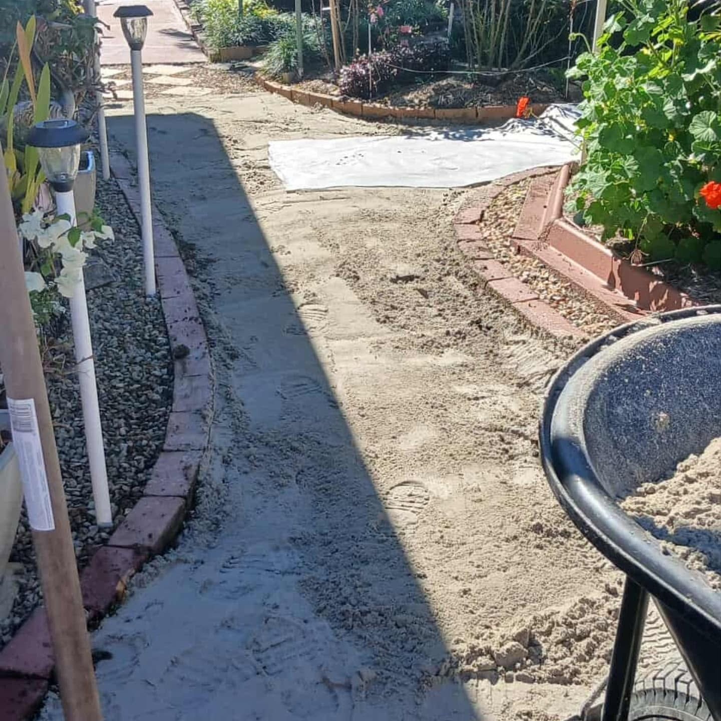Garden path under construction with fresh concrete and a wheelbarrow in the foreground