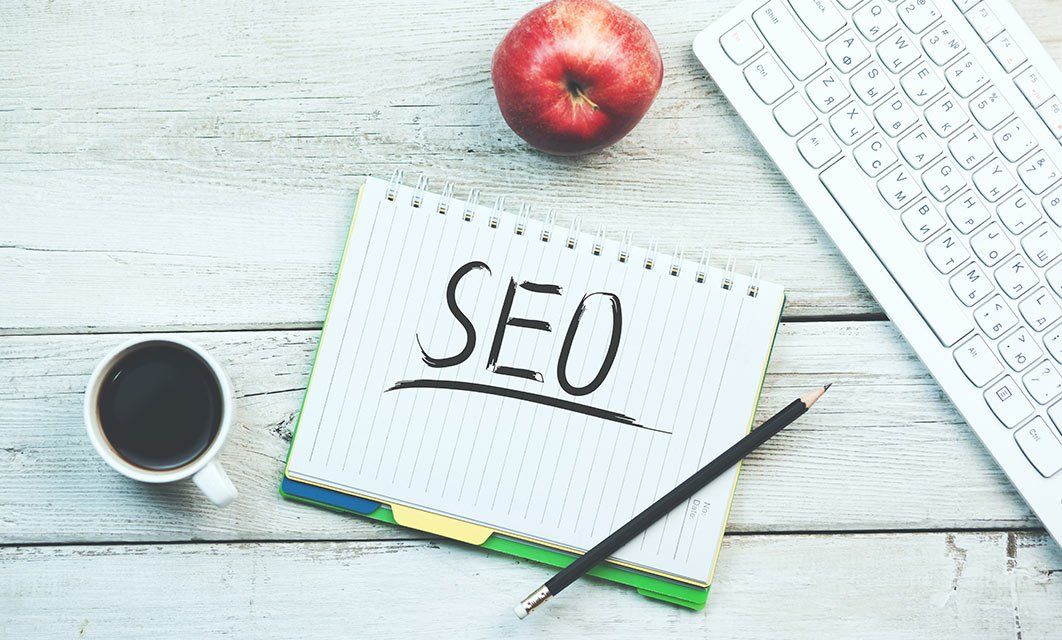 Website SEO-Textaufbau Block, Kaffeetasse, Apfel und Tastatur auf Holztisch