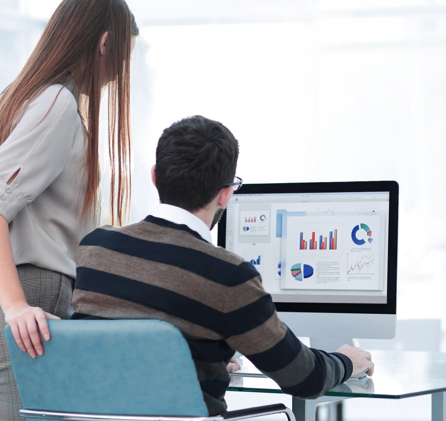 Frau und Mann schauen auf einen Computerbildschirm mit Grafiken und Diagrammen.