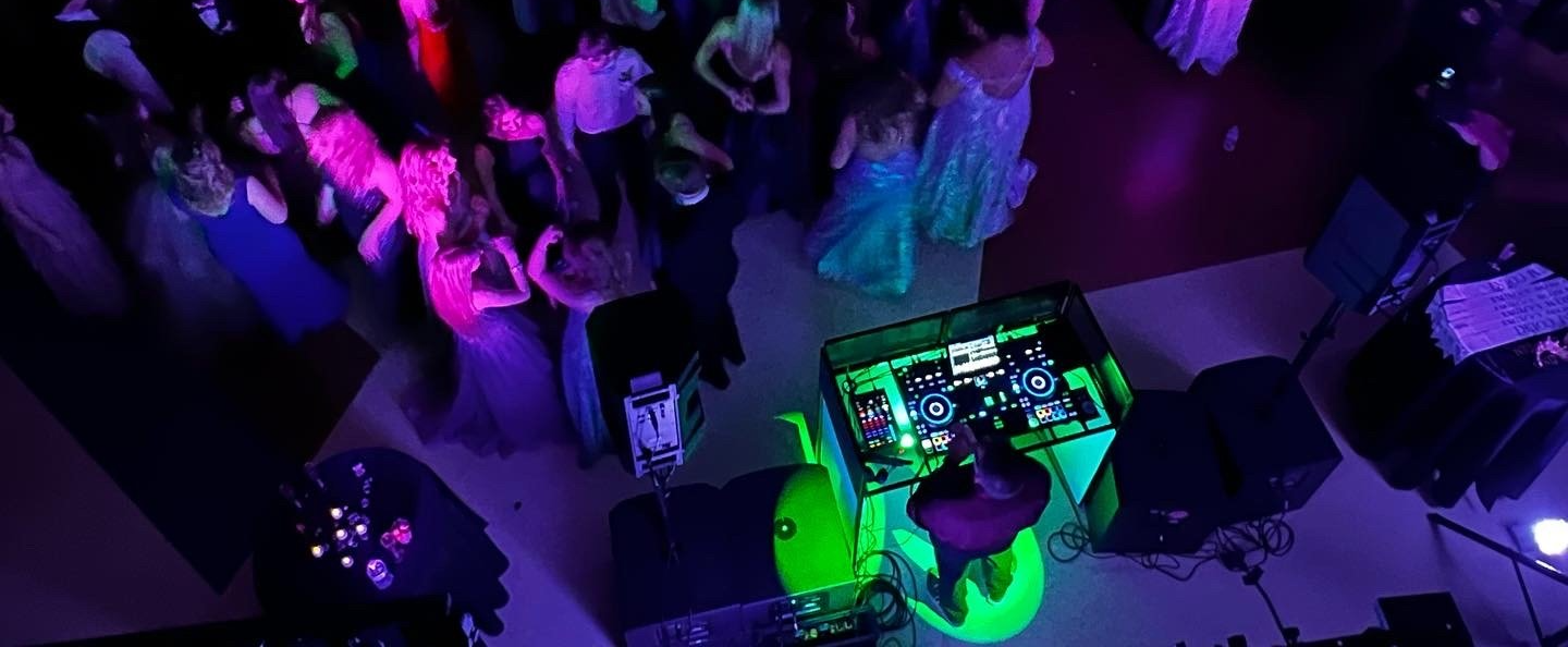 A dj is playing music in front of a crowd of people at a party.