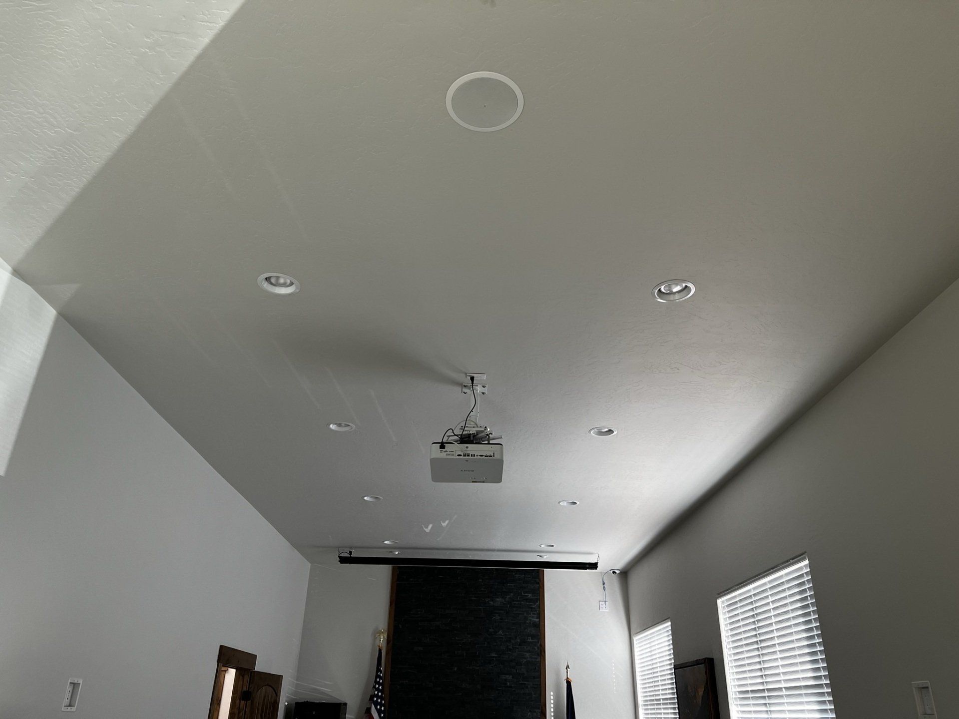 A living room with a projector hanging from the ceiling