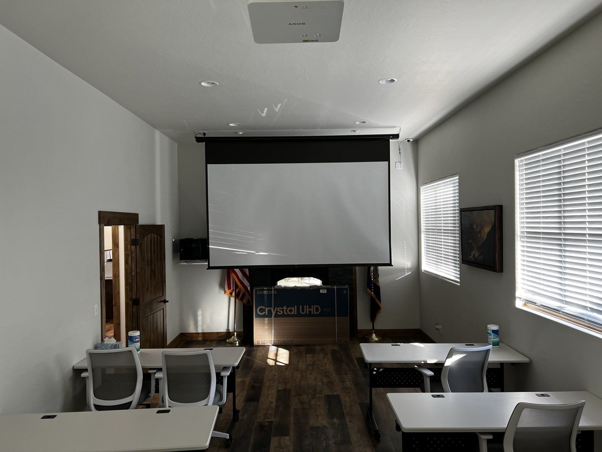 A classroom with tables and chairs and a projector screen
