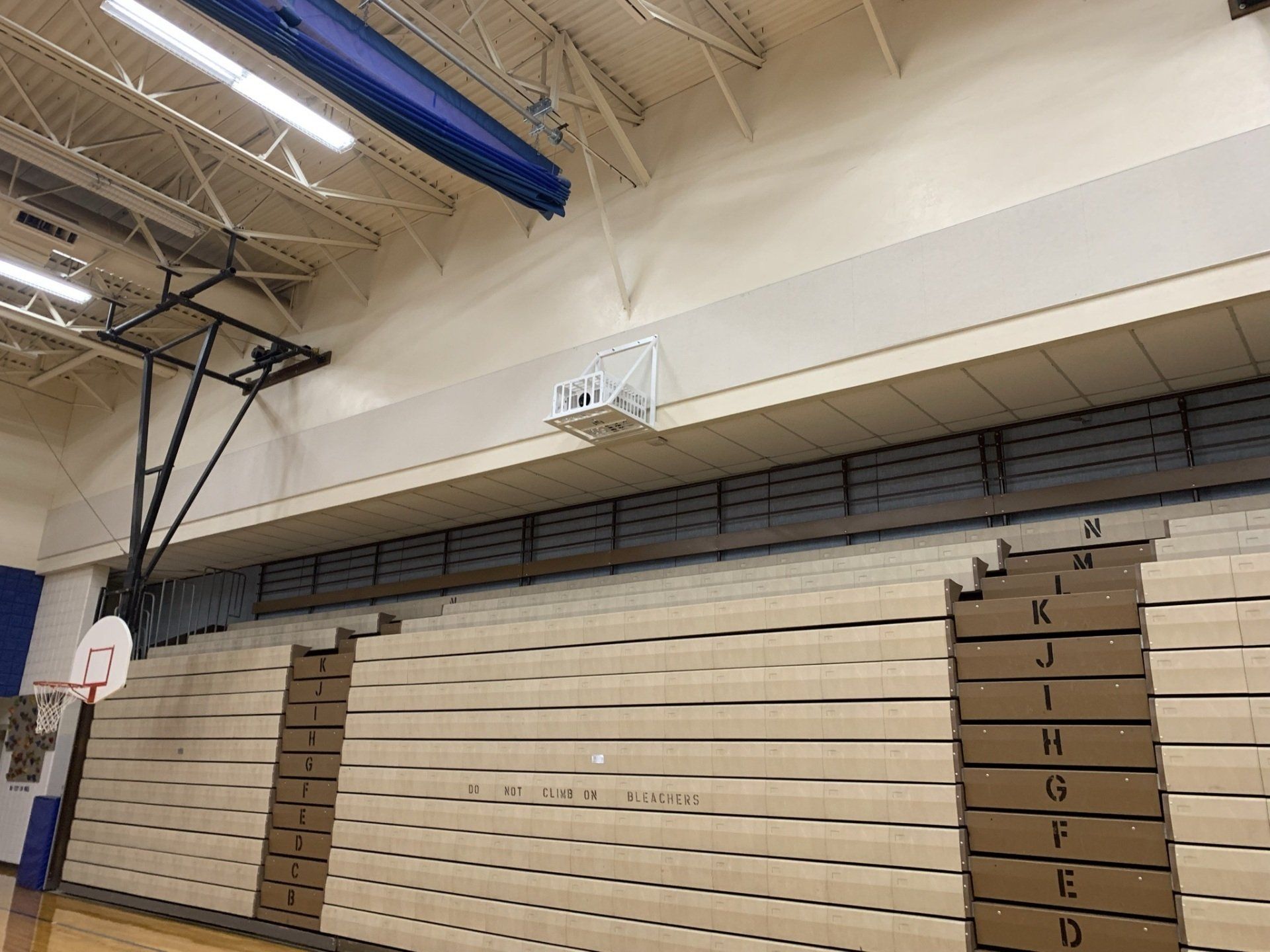 A basketball hoop is hanging from the ceiling of a gym