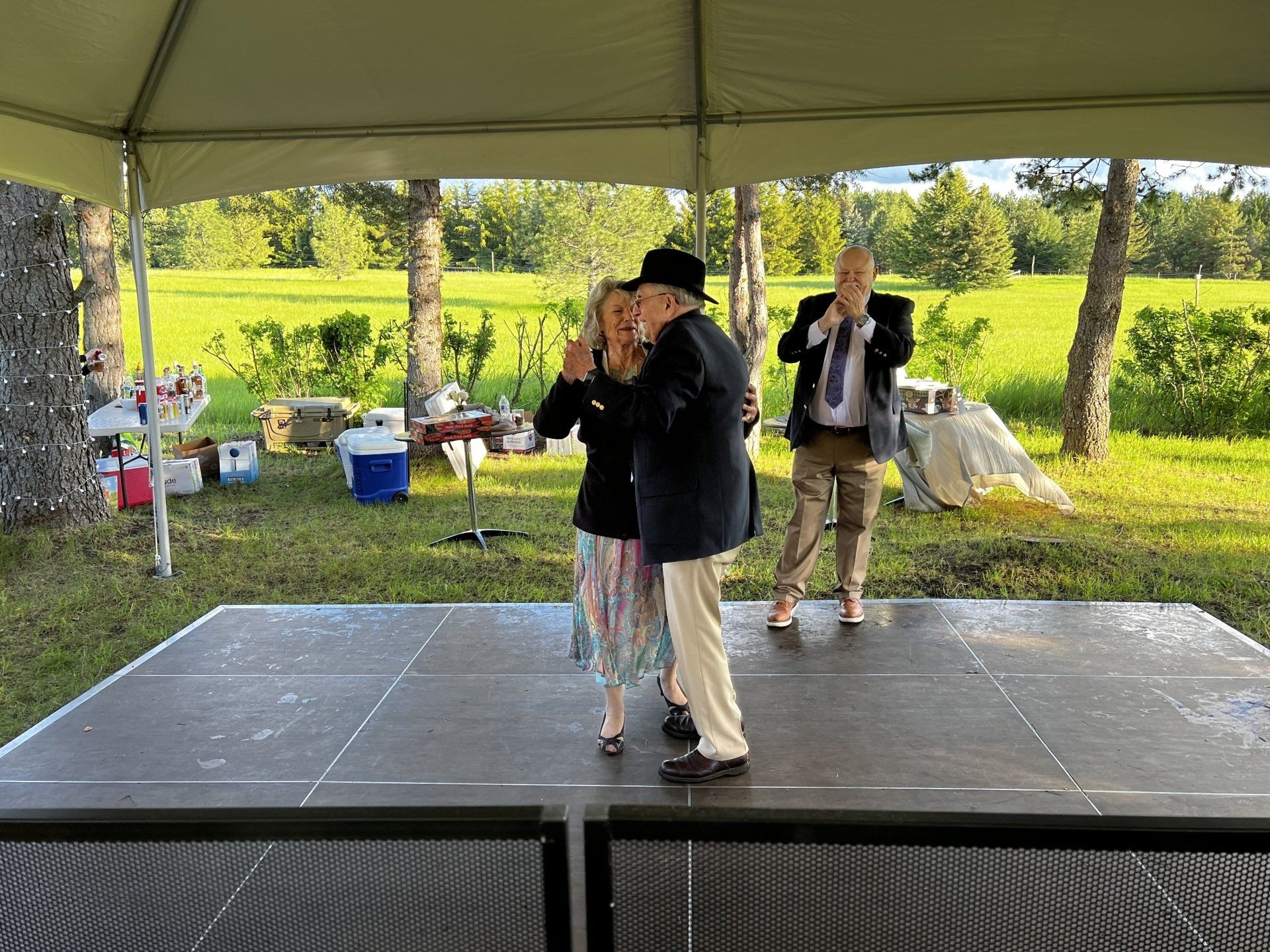 A man and woman are dancing on a stage under a tent.