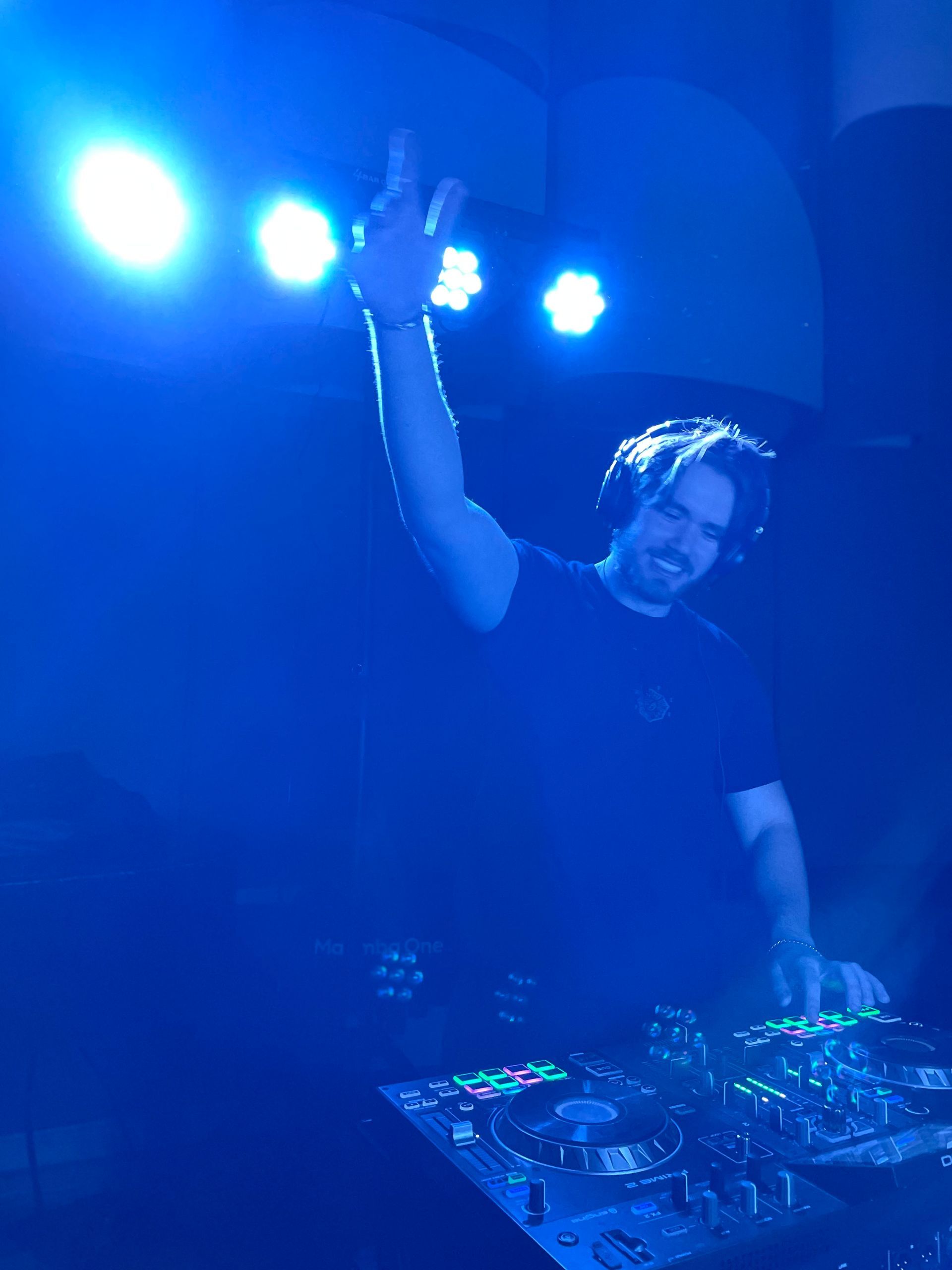 A man wearing headphones is playing music in a dark room