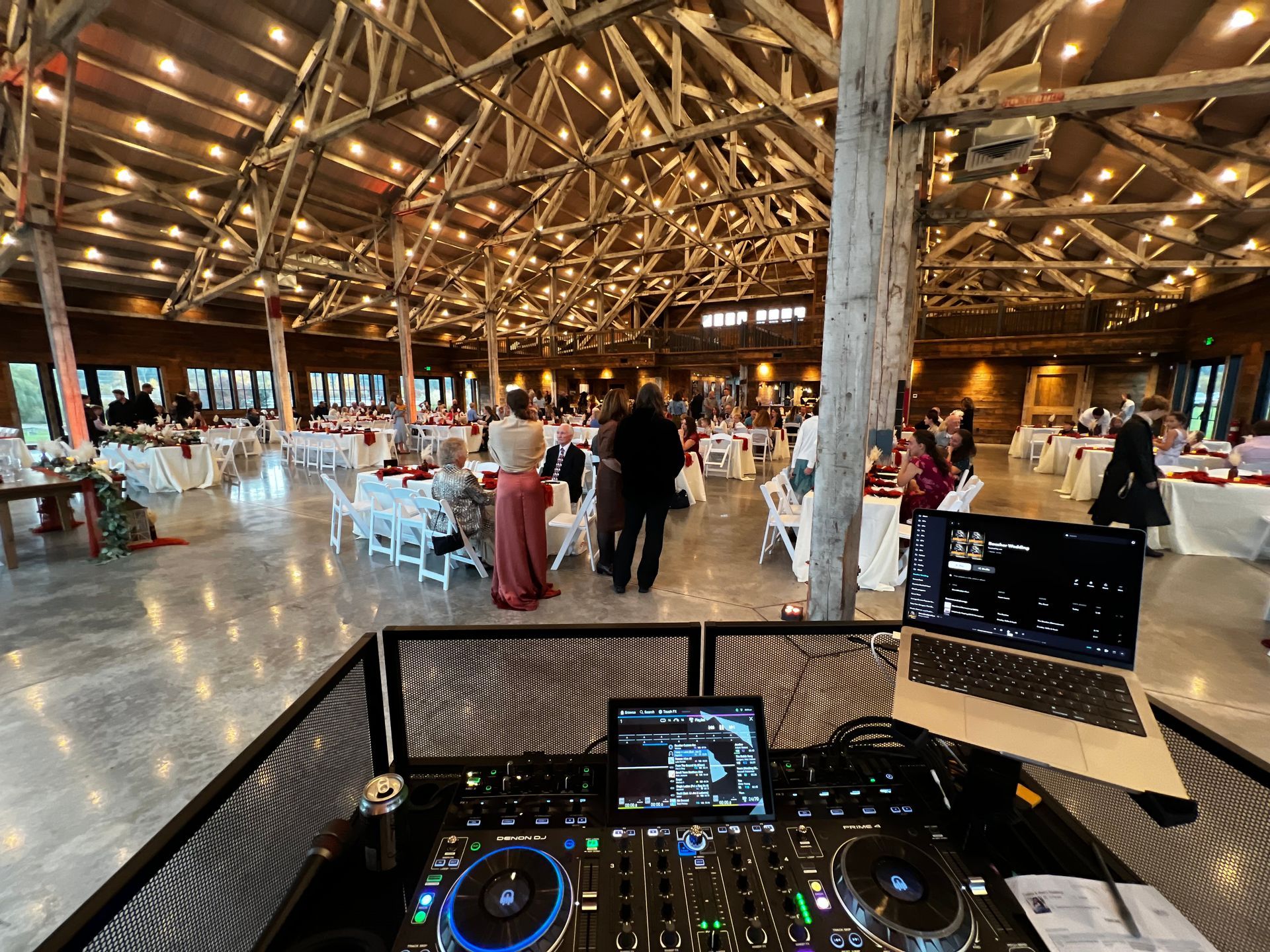 A dj is playing music at a wedding reception in a large room.