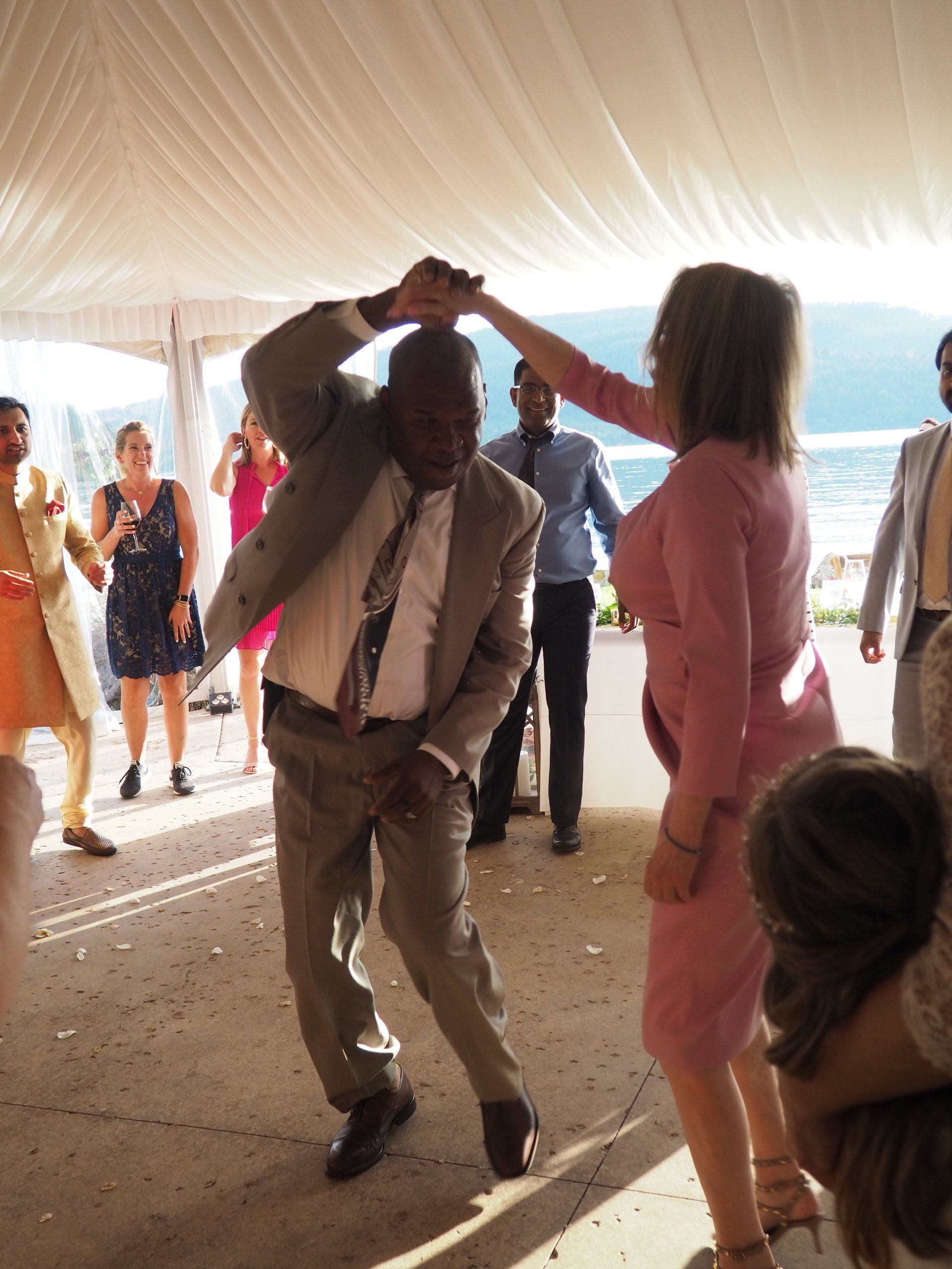 A man in a suit is dancing with a woman in a pink dress