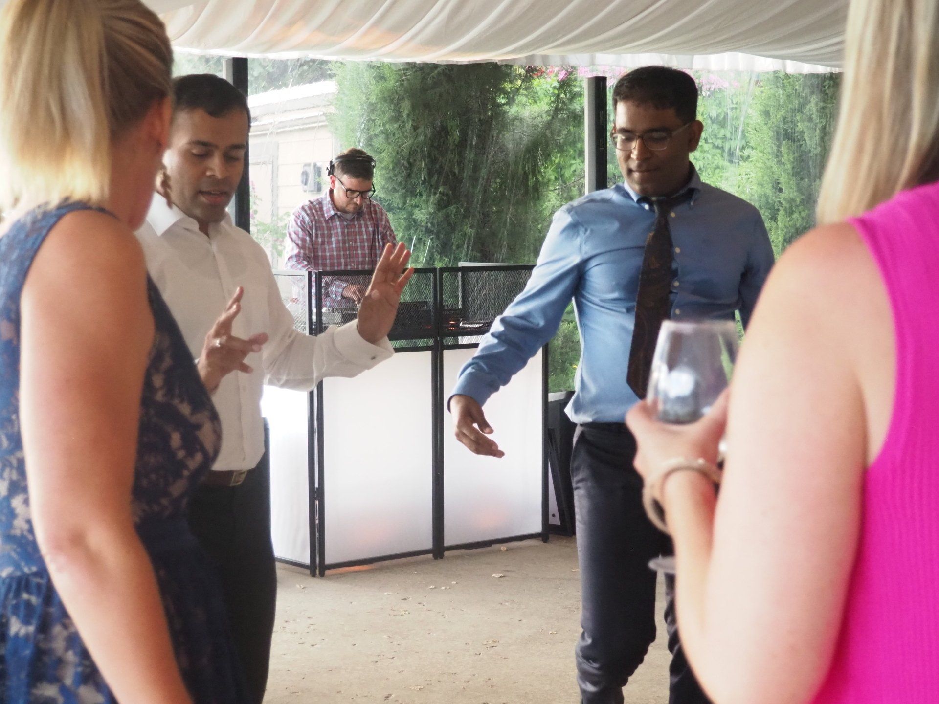 A group of people are standing in a room with a dj in the background.