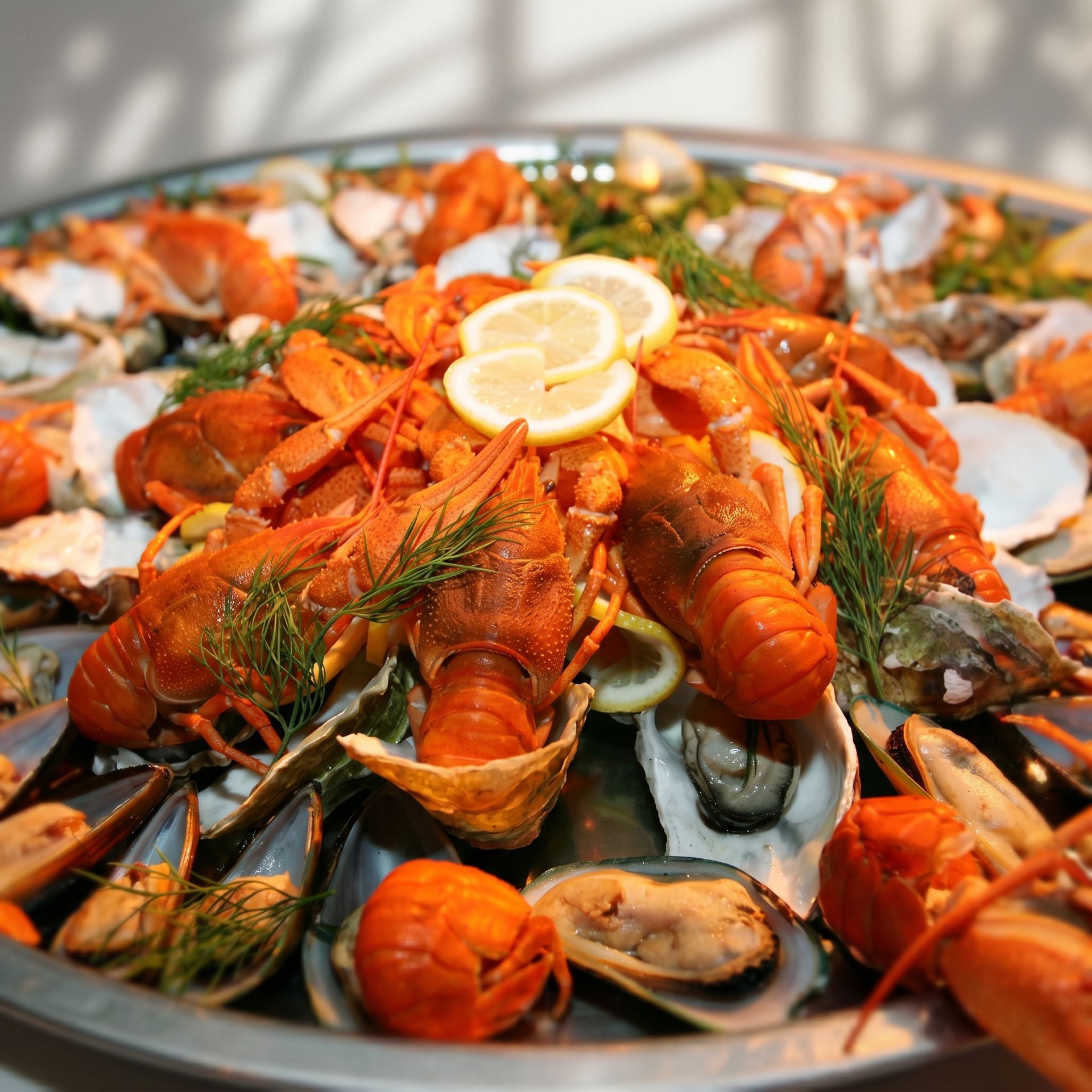 Seafood platter with orange lobsters, shrimp, mussels, and lemon slices on ice