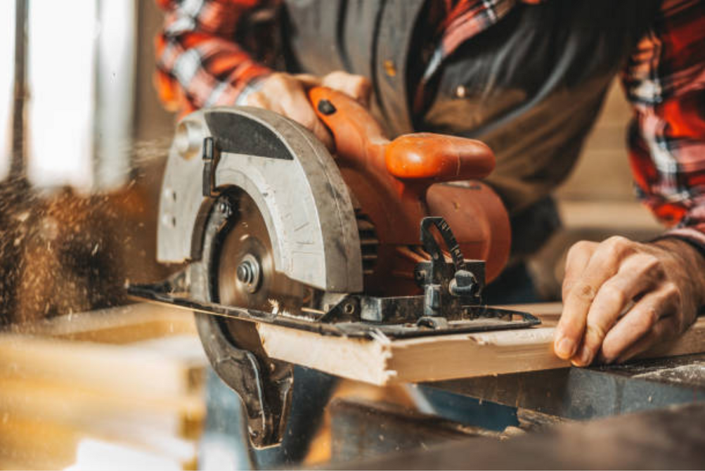 AD Construction NJ - Person using a circular saw to cut a piece of wood, generating sawdust.