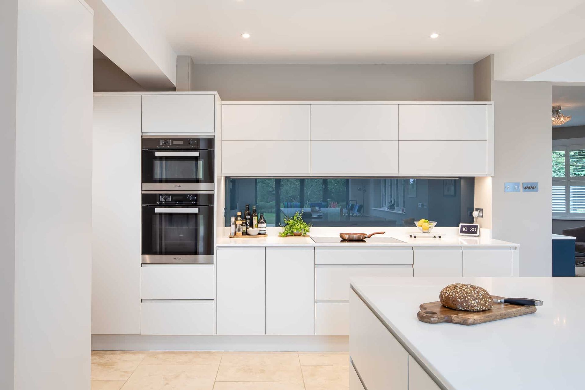 AD Construction NJ - Modern white kitchen with built-in ovens, sleek cabinetry, and a countertop island.