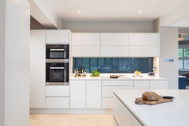 AD Construction NJ - Modern white kitchen with built-in ovens, sleek cabinetry, a light countertop.