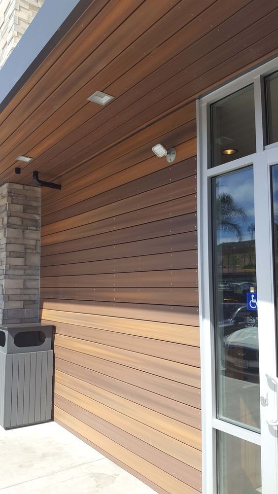 AD Construction NJ - Exterior of a building with wood siding and a glass door. Grey trash can on the left.