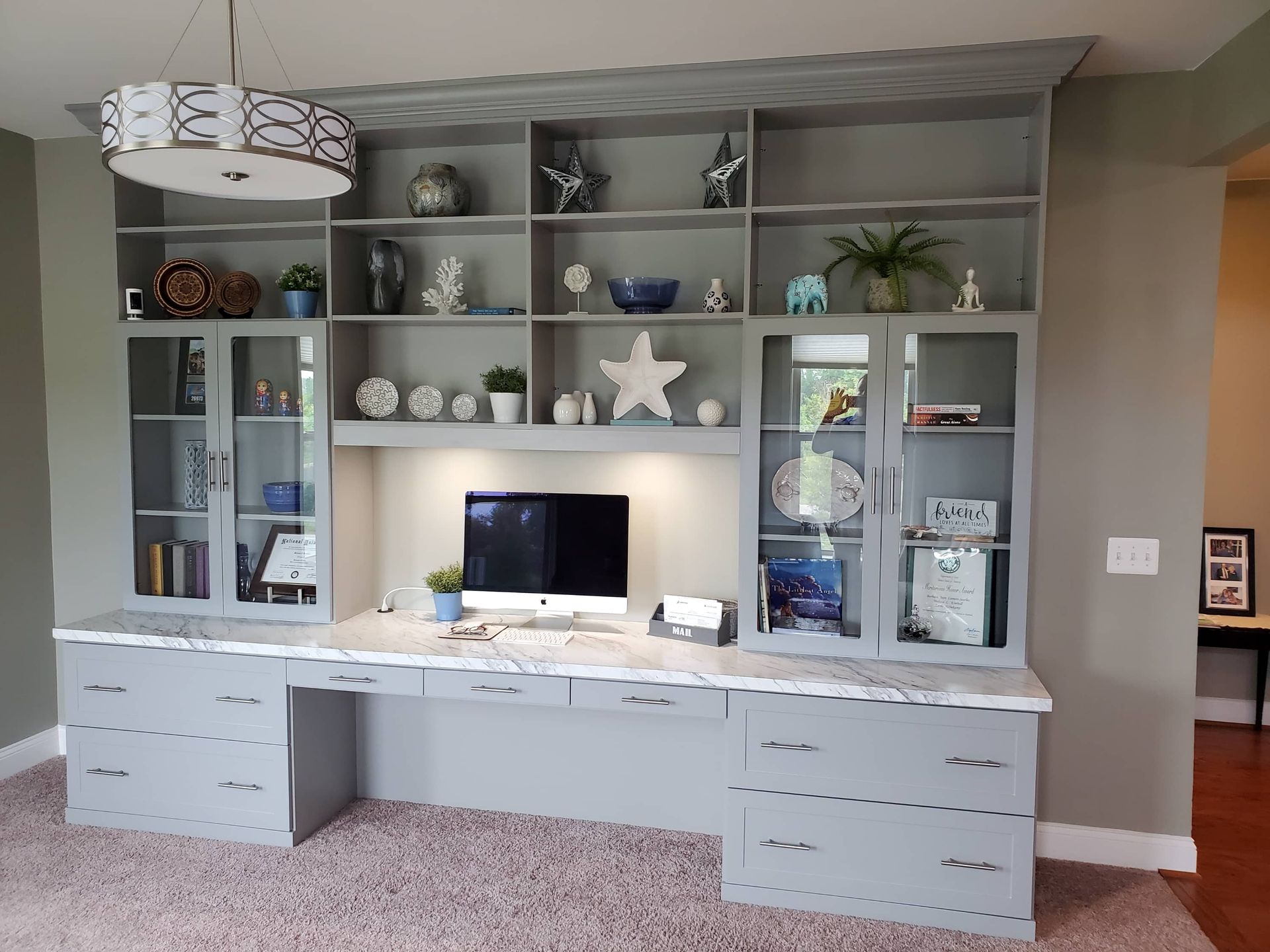 AD Construction NJ - Gray built-in desk with shelving, cabinets, and a computer against a gray wall.