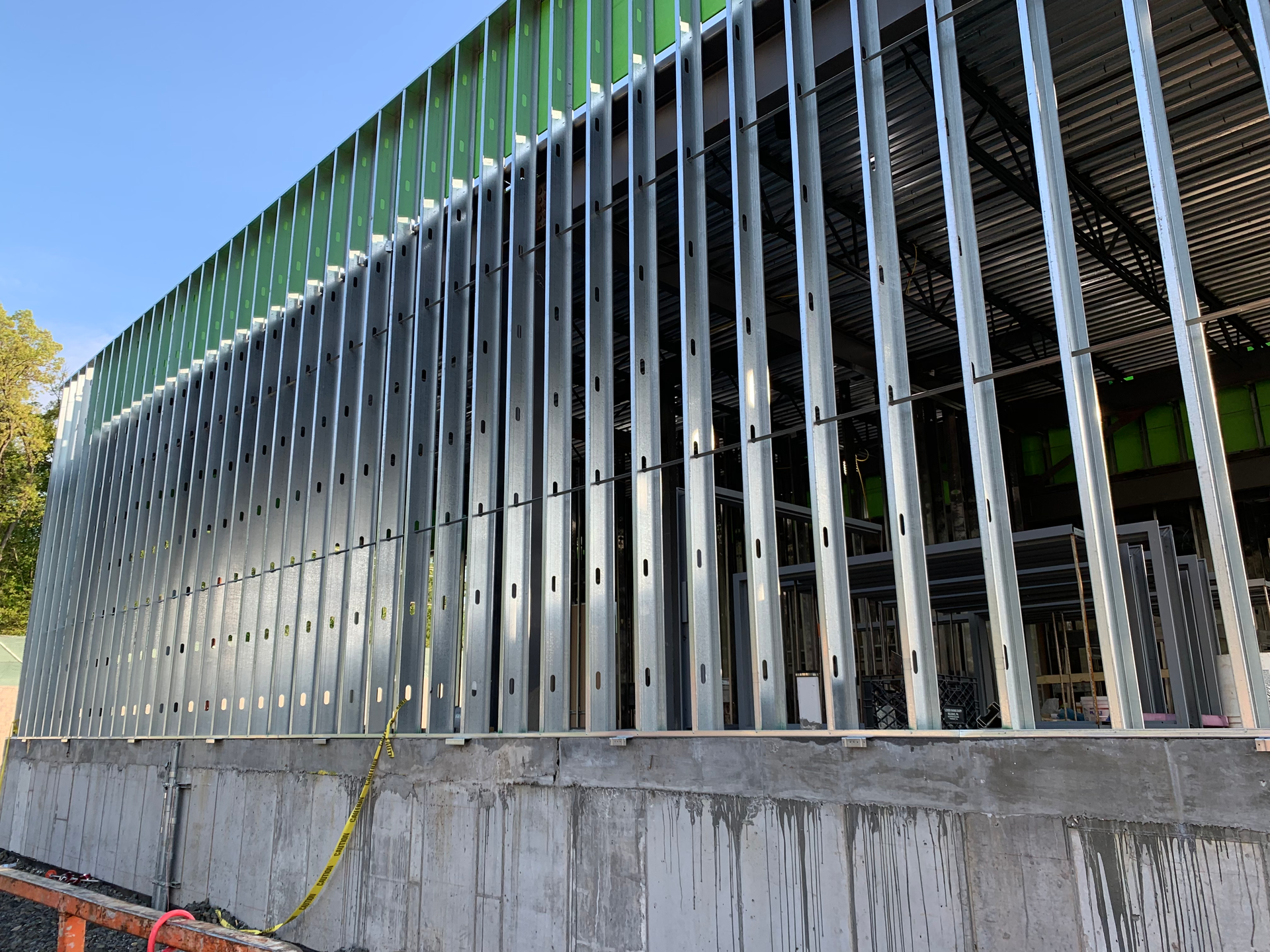 AD Construction NJ - Steel framing on a concrete foundation; building under construction, exterior view and green panels.