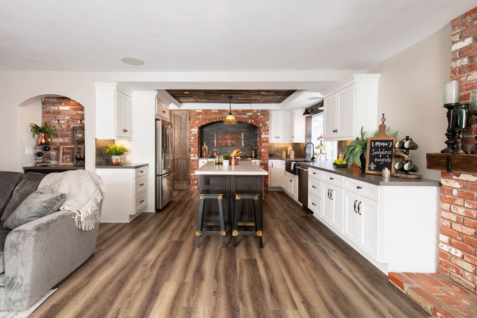 AD Construction NJ - Open-concept kitchen with island, white cabinets, brick accents, and wood-look flooring.