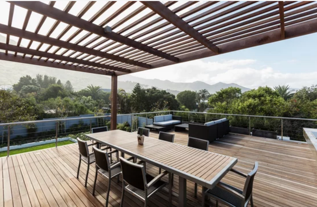 AD Construction NJ - Outdoor deck with wooden furniture, pergola, and mountain view.