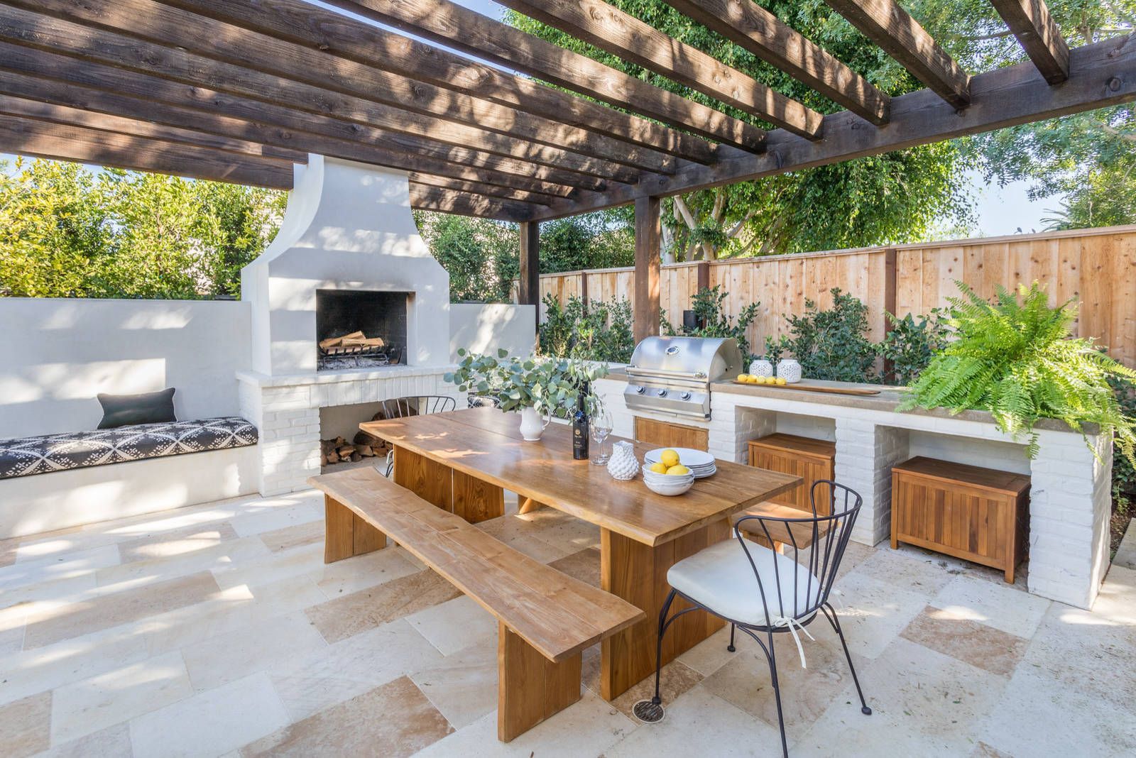 AD Construction NJ - Outdoor patio with fireplace, dining table, and built-in grill under a wooden pergola.