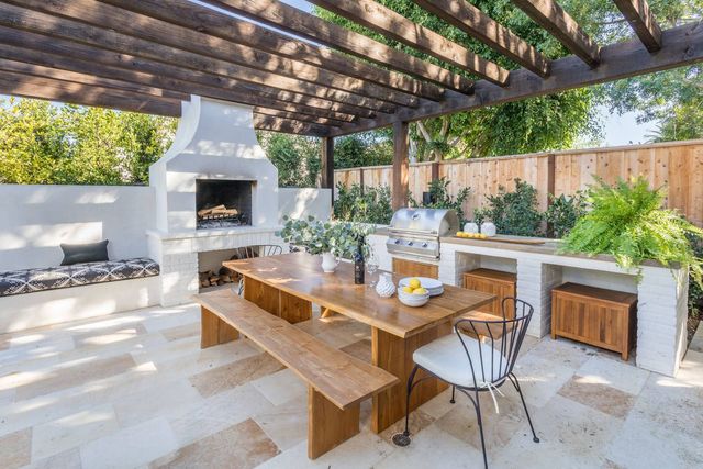 AD Construction NJ - Outdoor patio with a wooden table, built-in grill, fireplace, and pergola.