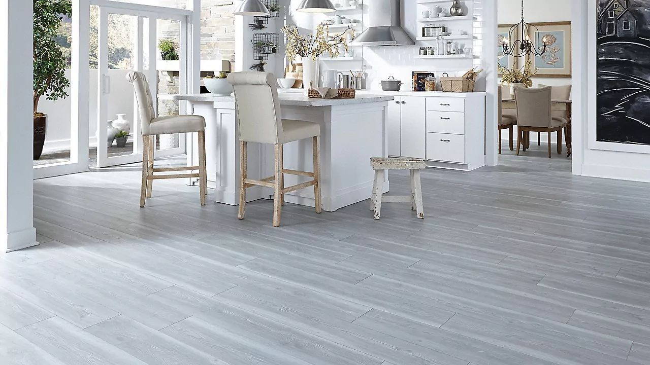 AD Construction NJ - Spacious kitchen with a white island and light gray hardwood floors. Two bar stools.