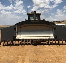 A bulldozer is parked in the middle of a dirt field.