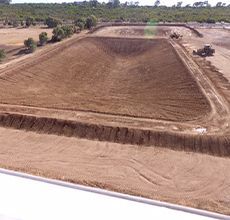 An aerial view of a large dirt field with trees in the background.