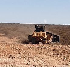 A bulldozer is sitting in the middle of a dirt field.