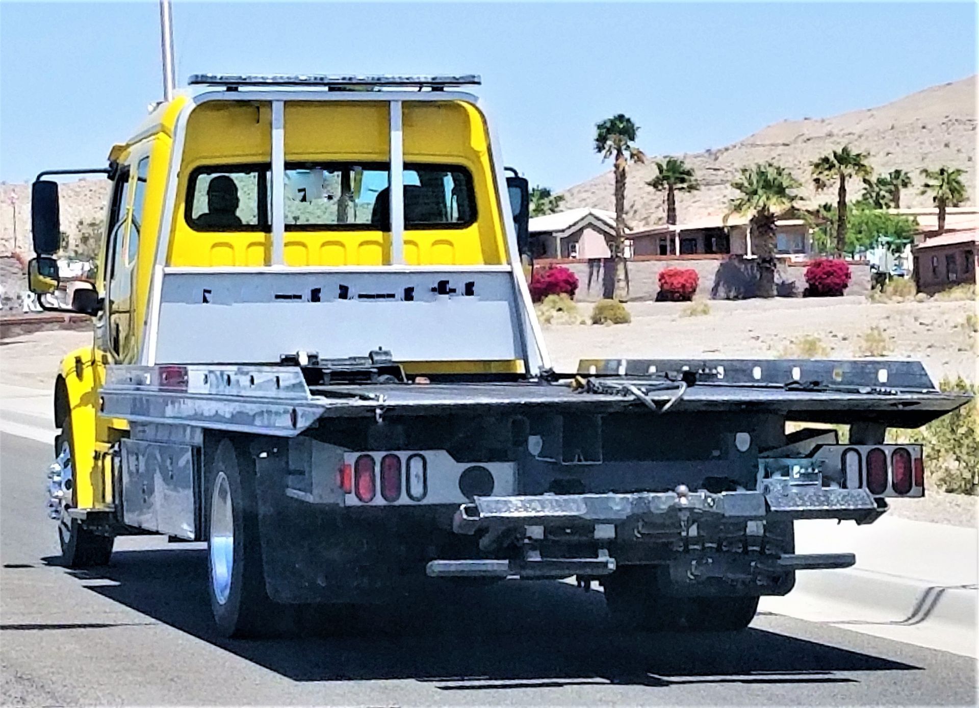 A yellow tow truck is parked on the side of the road