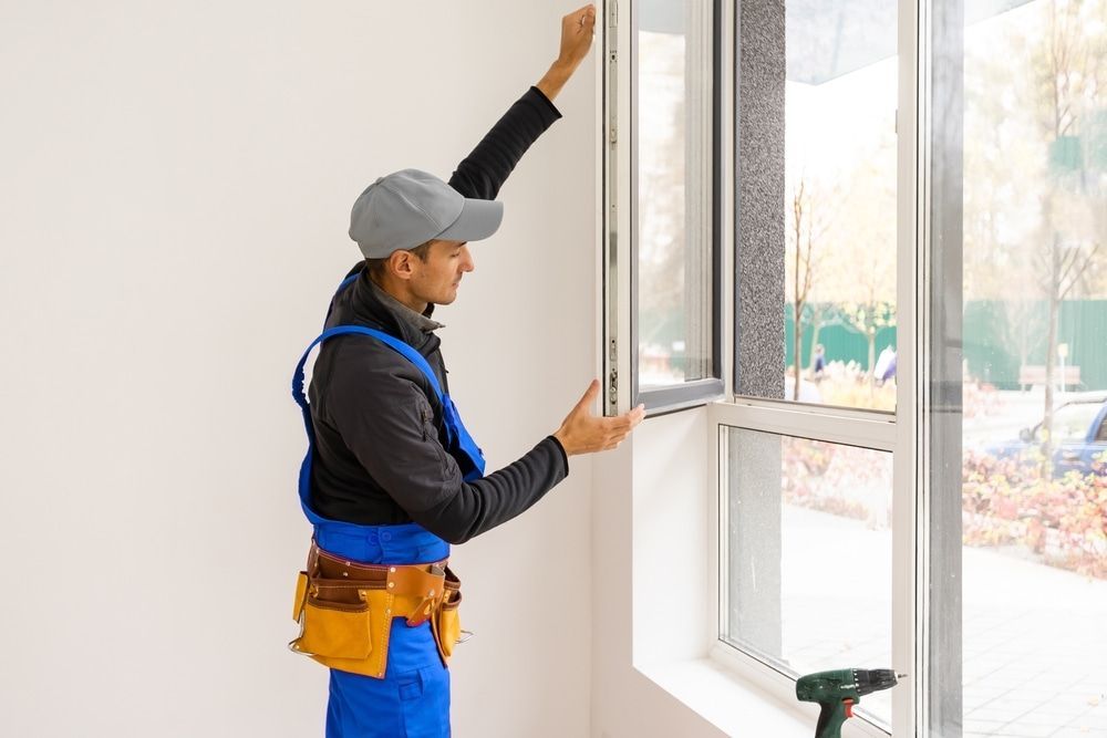 A Man Is Installing A Window In A Room — Datco Aluminium Pty Ltd In Murwillumbah, NSW