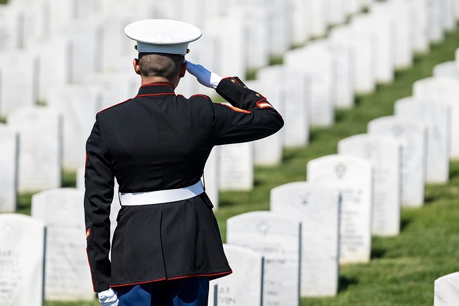 Marine salutes in Arlington National Cemetery, white headstones in the background.