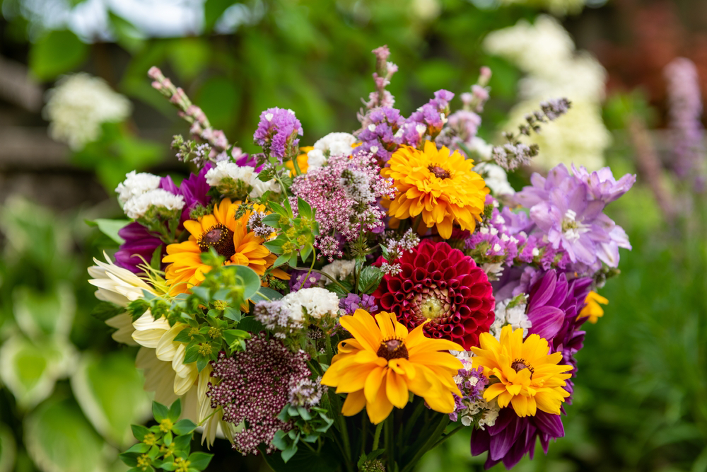Colorful bouquet of yellow, orange, and purple flowers with green foliage, blurred background.