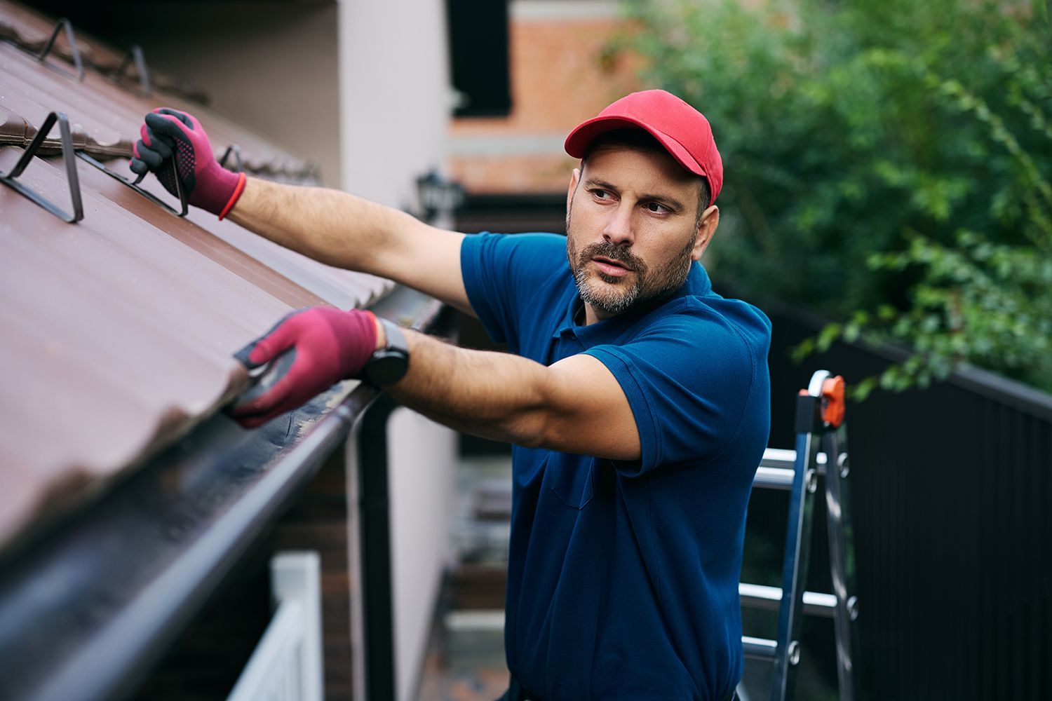 A male worker inspects the roof and gutter of a house.
