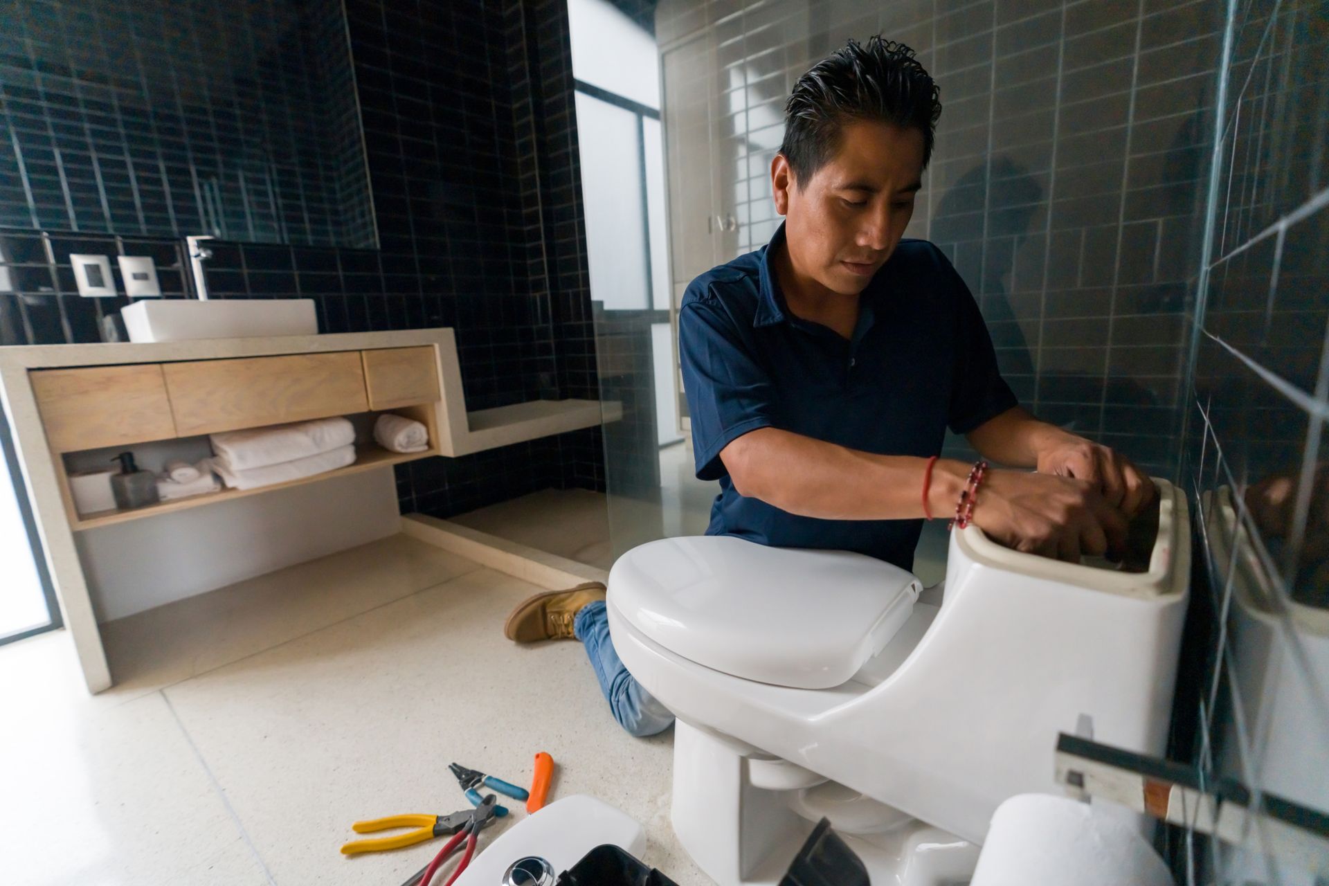 Plumber fixing a toilet in the bathroom.