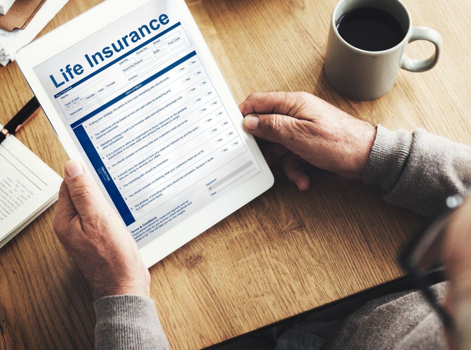 A man is holding a tablet with a life insurance form on it.  