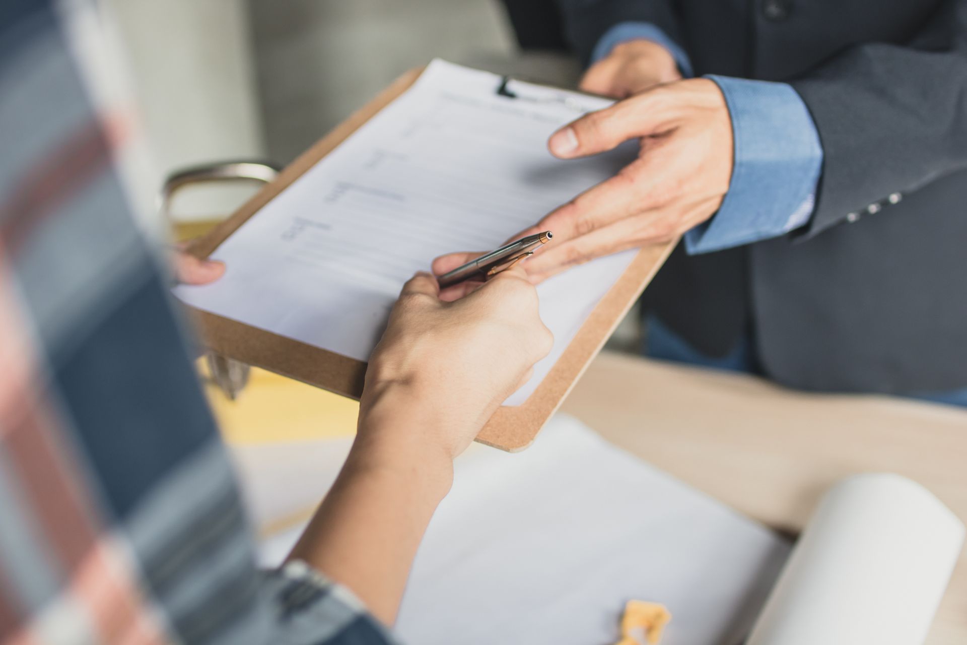 A man is giving a clipboard to a woman who is writing on it. 