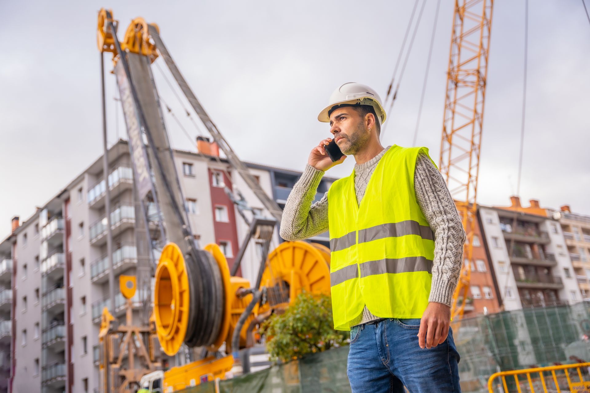 A construction worker is talking on a cell phone at a construction site.